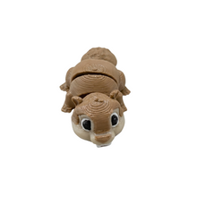 Inquadratura ravvicinata e leggermente dall'alto in primo piano di un modellino articolato Namii Mini Marmotta in plastica marrone chiaro, con corpo snodato, dettagli del musetto definiti ed occhi neri.