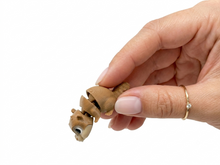 Primo piano di una persona che tiene delicatamente tra le dita della mano un piccolo modellino articolato Namii Mini Marmotta, che ne mostra la flessibilità degli snodi e le dimensioni in miniatura.